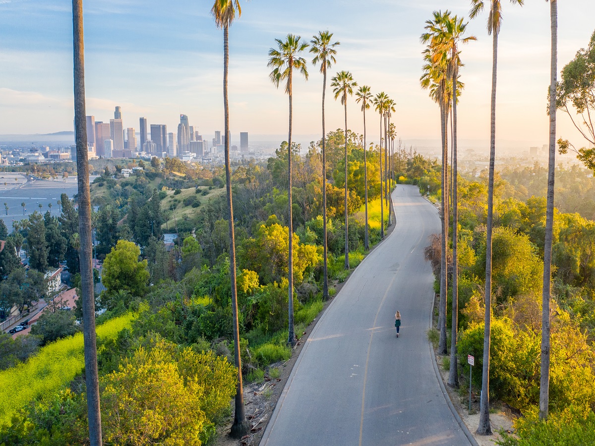 1143355576 Drone shot of a woman walking down a street toward Downtown Los Angeles.