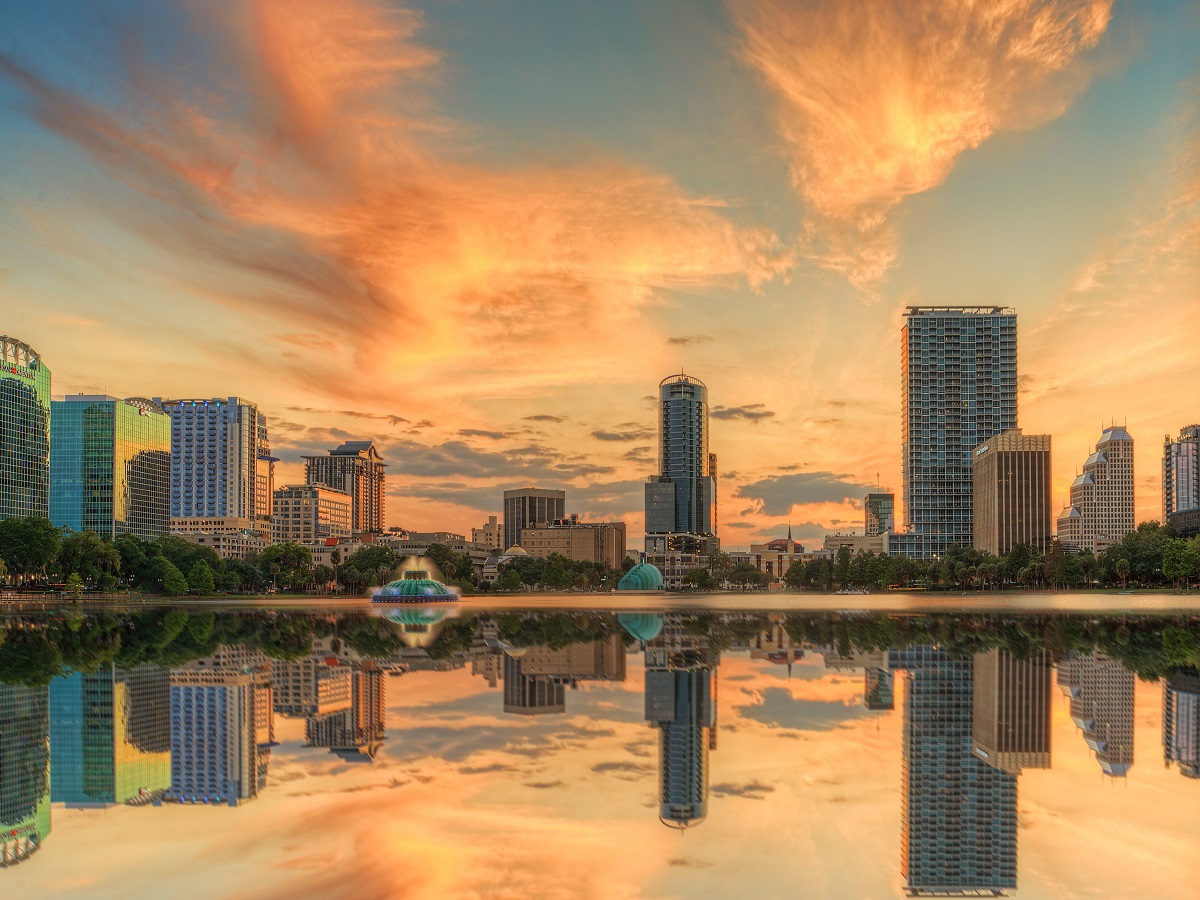 582224449 A colorful sunset over Lake Eola and Orlando, Florida with reflections captured off the lake.